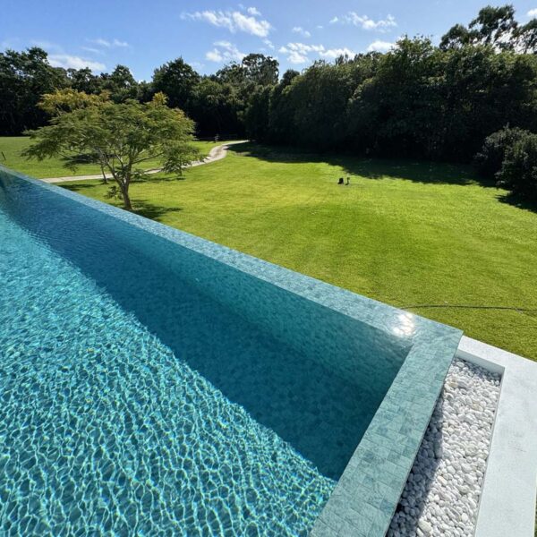 Feature spa wall finished with Blue Wave ceramic mosaic tiles, creating a dramatic drop-edge look in a modern backyard.
