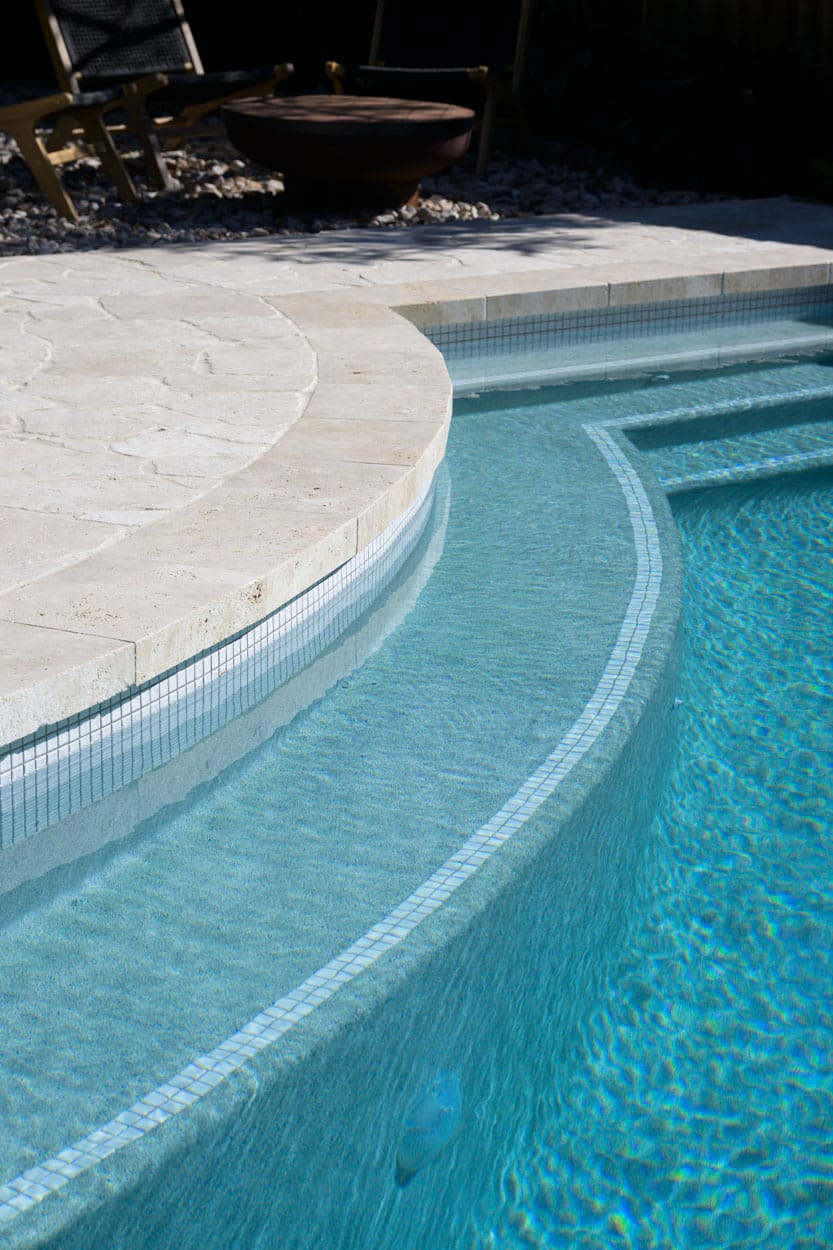 CMC555 White Wavy 23mm 2 a pool with a travertine crazy pave curved walkway