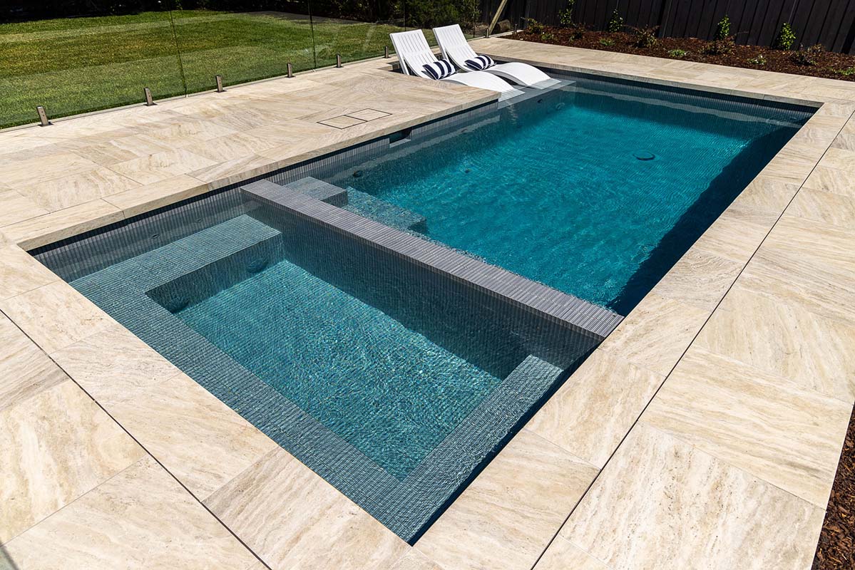 CMC655 Druid Grey KitKat Fully-Tiled Pool and Spa + Coastal Cream Travertino Dropface coping and surrounds.