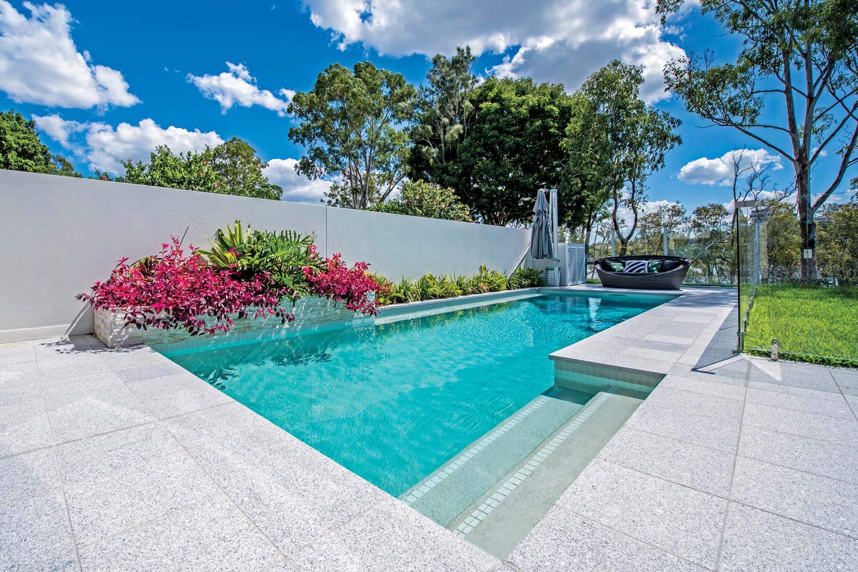 Light Grey Granite pool coping and surround tiles with White Crystal glass waterline and Gold Stone cladding