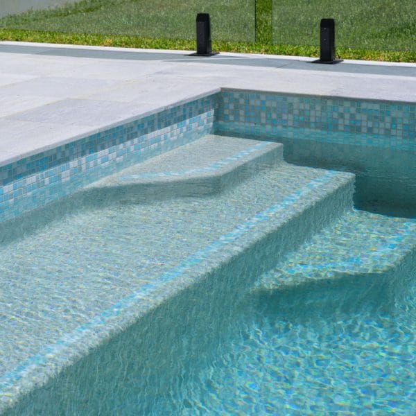 Parisian Blue Limestone square edge coping and surround tiles paired with GC452 Calypso glass mosaic waterline.