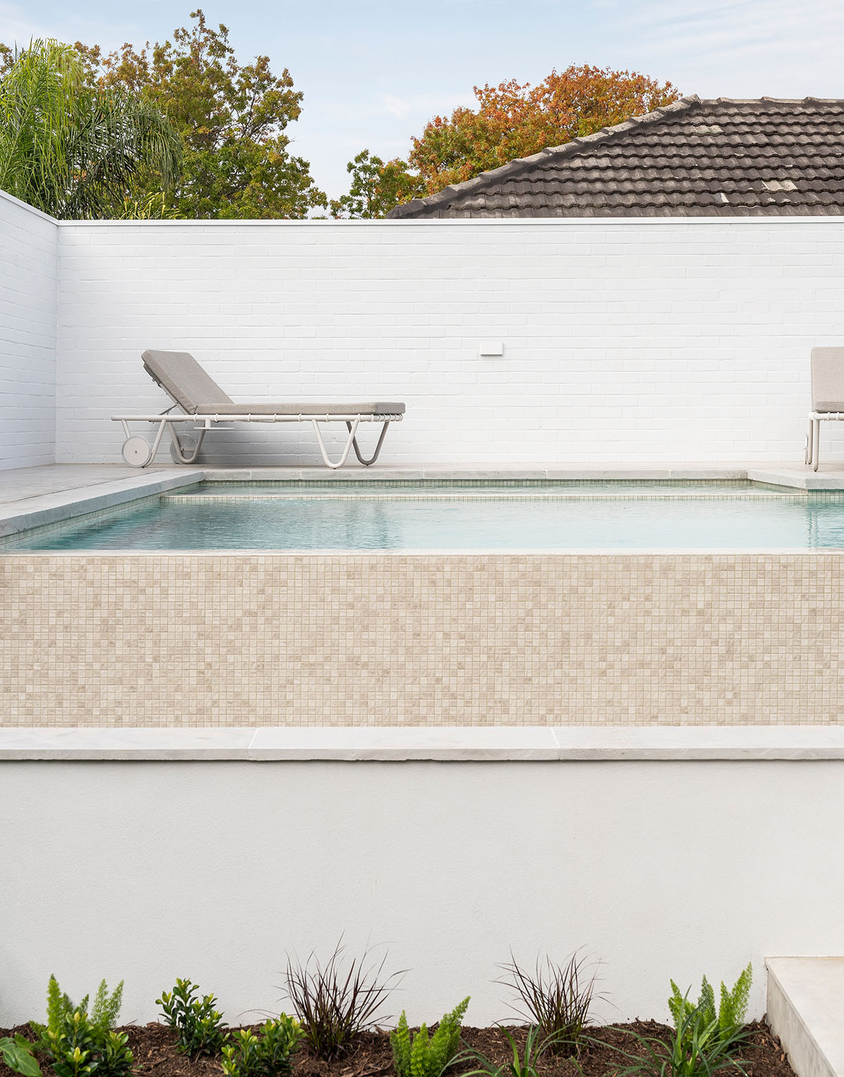 Wide lifestyle shot of a Mediterranean-style pool with Luna Wavy ceramic mosaics.