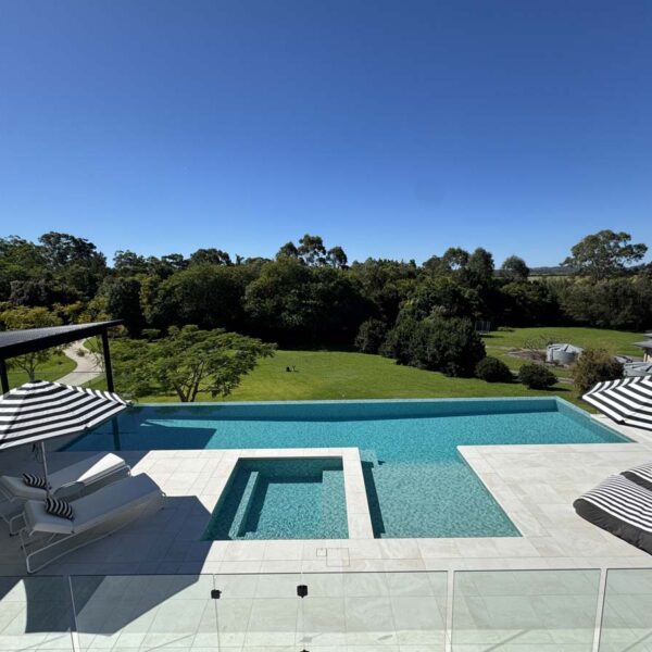 Angled overhead view of a modern rectangular pool and spa finished with Bianco Marblano porcelain tiles, installed by Baldwin Aquatic in Queensland.