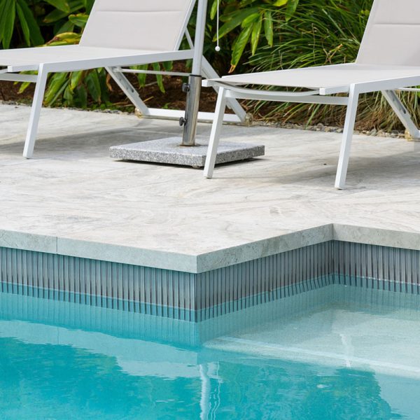 Rustic grey travertine lookalike as dropface coping and surround tiles, paired with grey kitkat waterline pool mosaics.