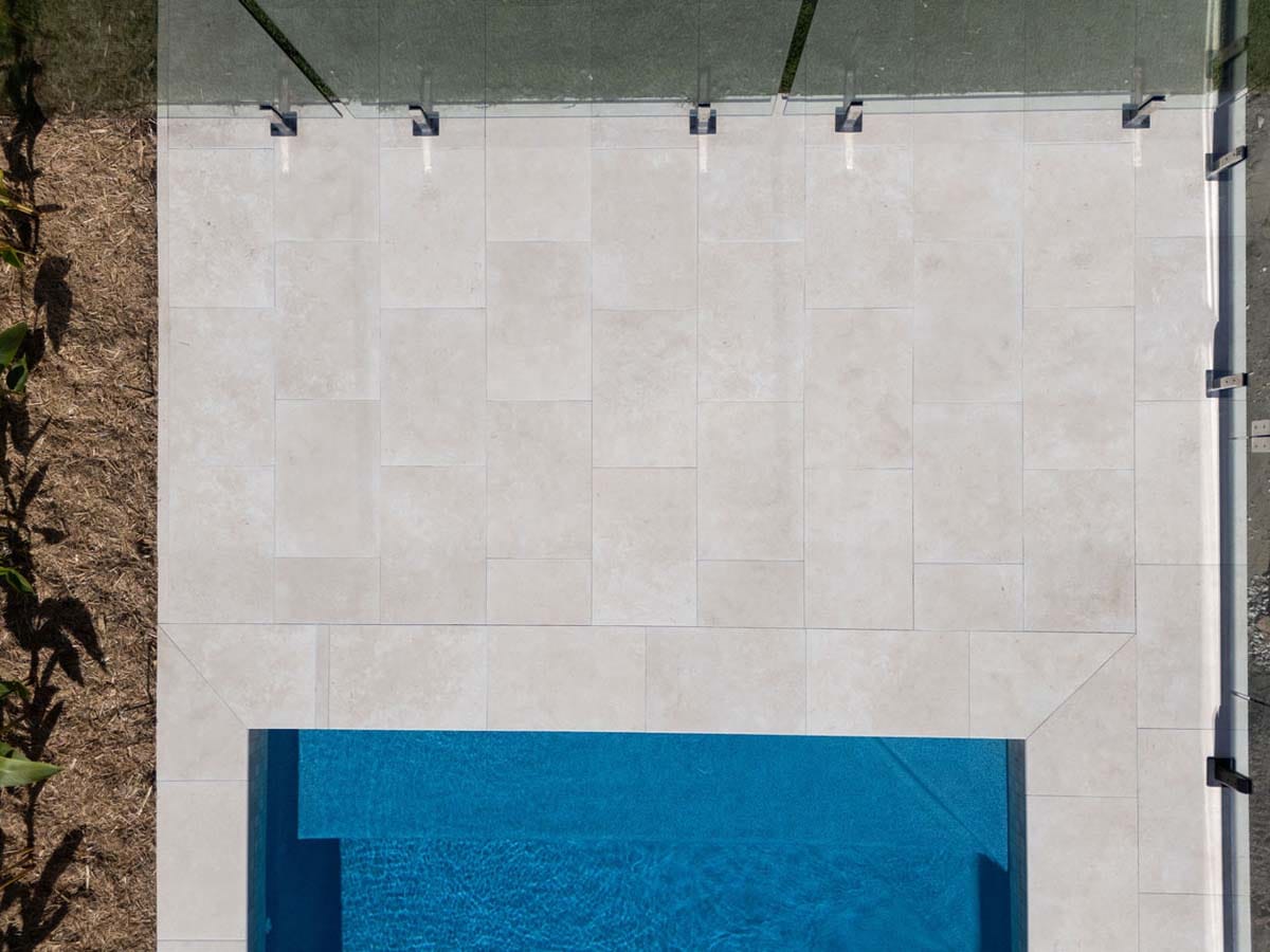 Flax Travertino - 20mm 3 Bird’s-eye view of creamy stone-look porcelain pool tiles with a neutral, timeless palette.