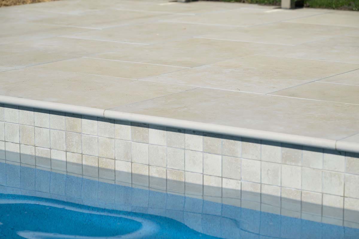 Flax Travertino - 20mm 2 Close-up of beige travertine-style porcelain tile in outdoor pool with timeless resort-style elegance.