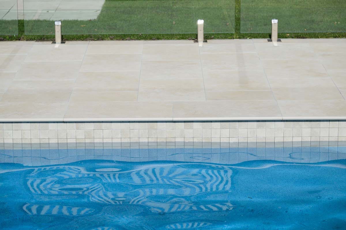 Flax Travertino - 20mm 6 Travertine-look porcelain tile at pool waterline, creating a light Mediterranean feel.