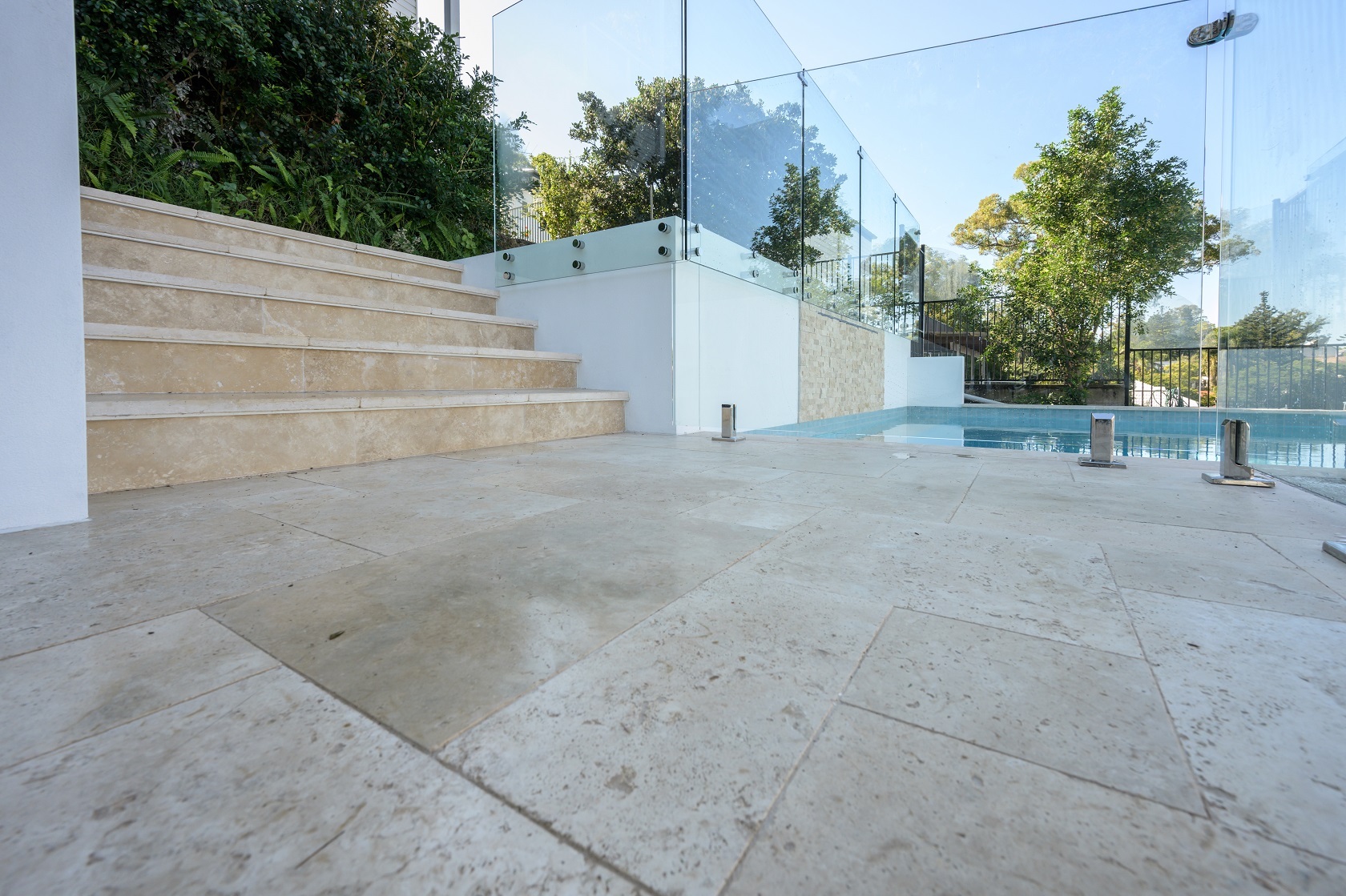 Linen Travertine pool coping and surrounds and stairs with Origami Ice Blue waterline tile and Linen Travertine cladding